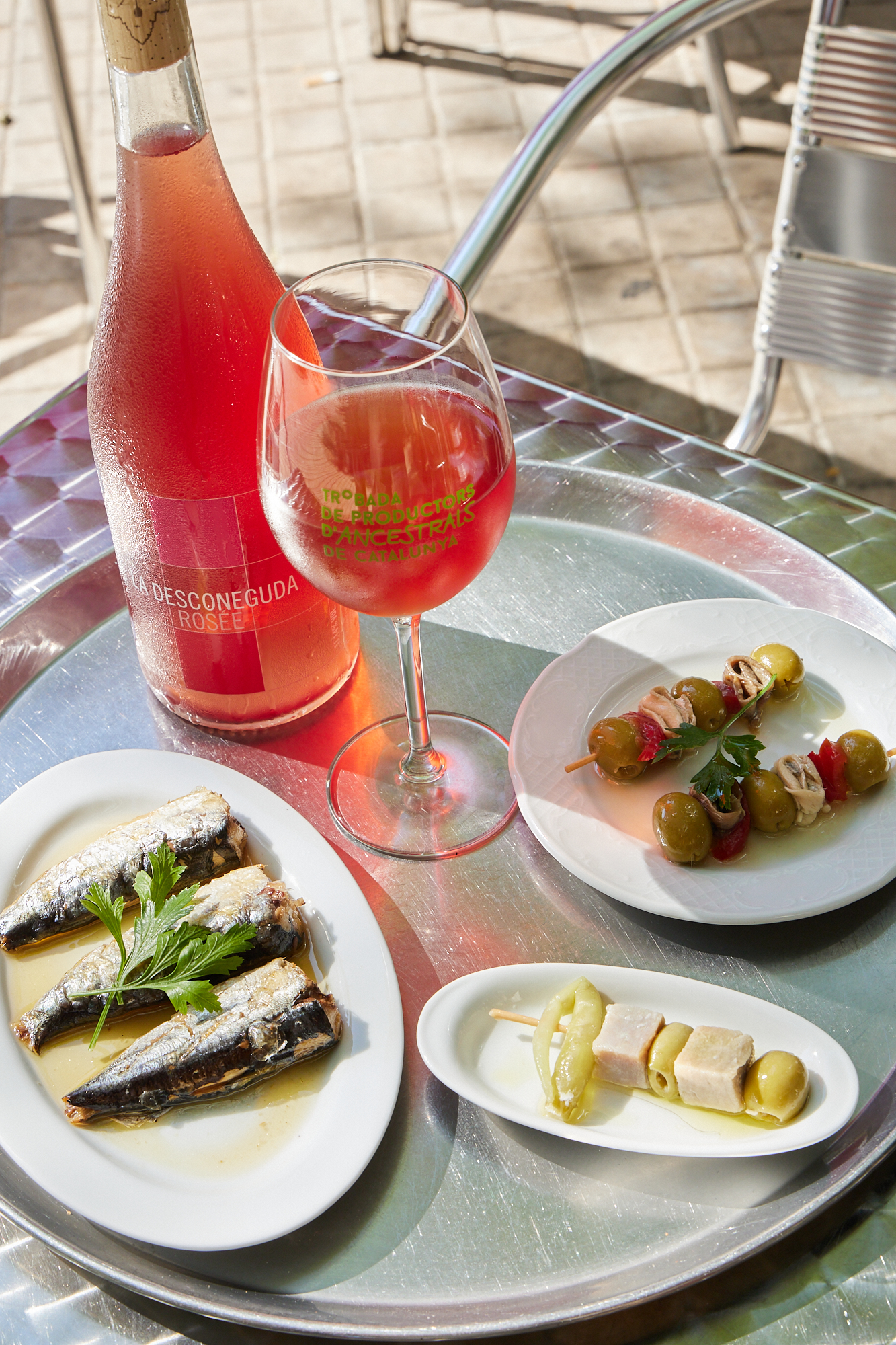 Sardinas, banderillas de olivas y una copa de vino rosado en la terraza de L’Estel